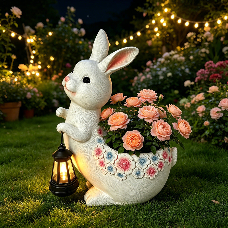 The Lantern Rabbit Planter in a cottage garden at dusk, lantern lit