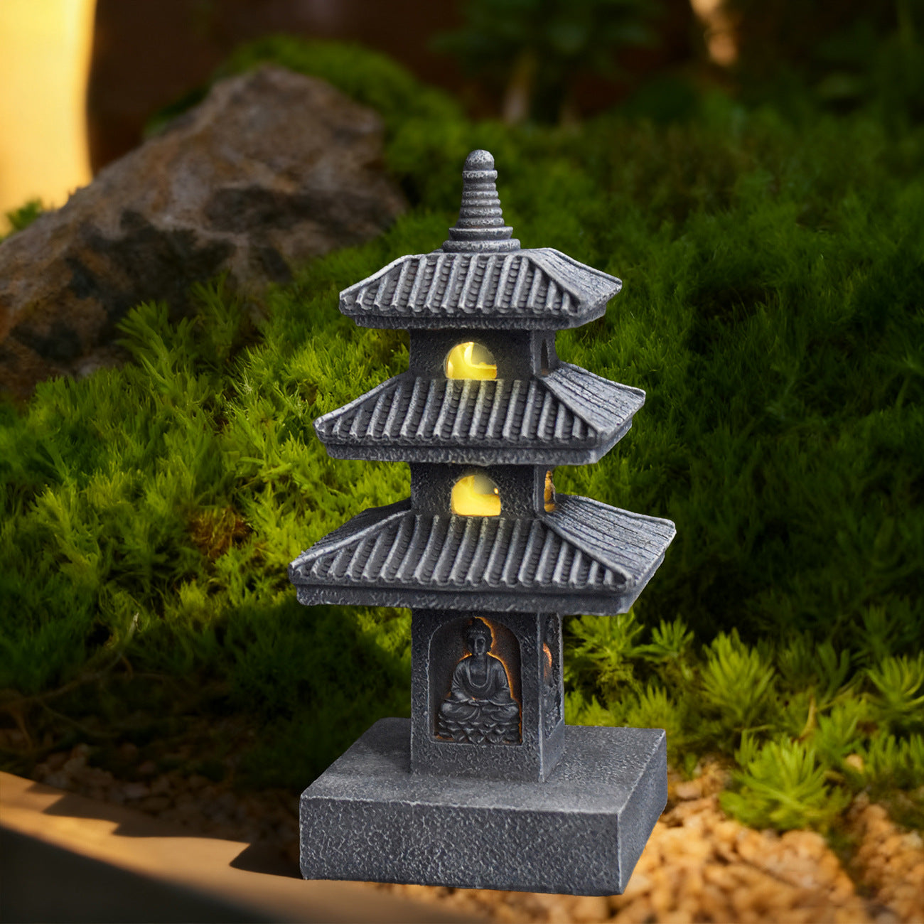 The Three-Storey Pagoda Lantern glowing warmly beside moss and stones