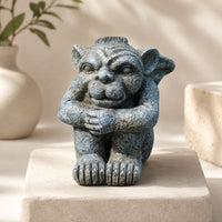 The Watcher Gargoyle sitting with folded arms and oversized feet