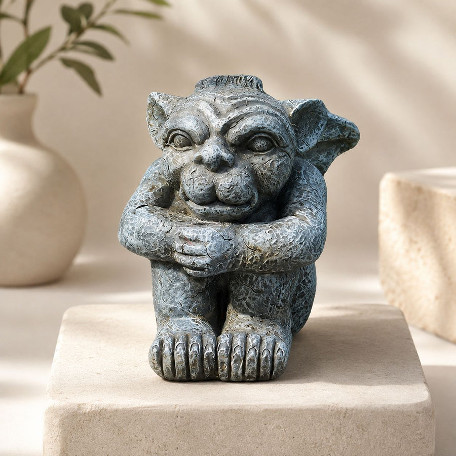 The Watcher Gargoyle sitting with folded arms and oversized feet