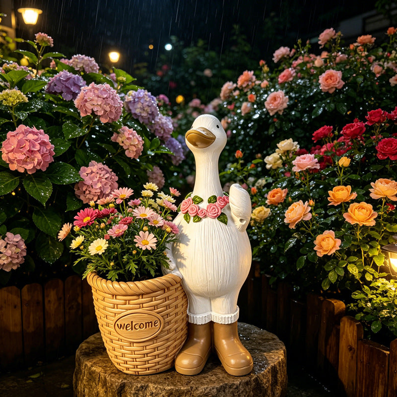 The Welcome Goose Planter with the basket planted with flowers in a garden bed